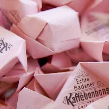 Ein Haufen Echter Badener Kaffeebonbons im rosa Wickelpapier mit dem Aufdruck von Carl Ullmann